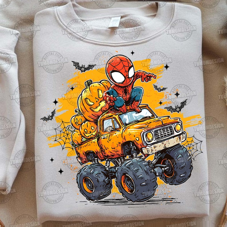 May include: A light beige sweatshirt featuring a Halloween-themed graphic. The design includes a cartoon Spider-Man character sitting on a monster truck filled with carved pumpkins. Bats, spiderwebs, and stars complete the festive scene.