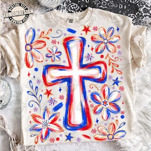 Op de afbeelding: Crèmekleurig T-shirt met een groot kruisontwerp in rood, wit en blauw, omringd door bloemen- en stermotieven. Het shirt heeft de tekst "DIGITAL FILE" en "TUMOMDESIGN CUSTOM FILE" erop gedrukt. Het ontwerp heeft een handgeschilderde uitstraling.