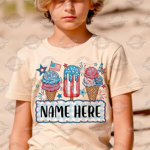 May include: A beige t-shirt featuring a patriotic design with ice cream cones, a popsicle, and an American flag. The shirt has the text "NAME HERE" in a blue and white checkered banner.
