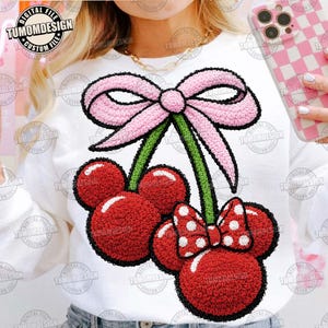 May include: White sweatshirt featuring a red cherry design with a pink bow and a Minnie Mouse-inspired bow with white polka dots. The design has a textured, embroidered appearance. The text "TUMOMDESIGN" is visible.