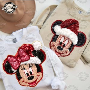 May include: Two sweatshirts featuring sequined Mickey and Minnie Mouse designs wearing Santa hats. One sweatshirt is white, the other is beige. The text "TUMOMDESIGN" is visible in the image.