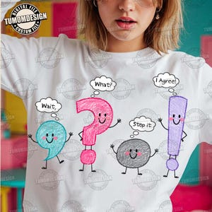Puede incluir: Una sudadera blanca de manga larga con un gráfico de cuatro signos de puntuación coloridos con brazos y piernas. Los personajes incluyen una coma azul que dice Wait, un signo de interrogación rosa que dice What, un punto gris que dice Stop it y un signo de exclamación morado que dice I Agree.