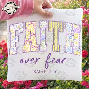 Könnte beinhalten: Weißes Kissen mit dem Schriftzug "FAITH over fear" in lila Schrift. Das Wort "FAITH" ist in großen, dekorativen Buchstaben mit Blumen- und Karomustern gehalten. Der Text "ISAIAH 41:10" befindet sich unten.