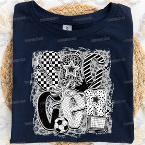 May include: Navy blue t-shirt with a white graphic design of the word "Soccer" in a stylized font. The graphic includes a soccer ball, a goal, and stars.