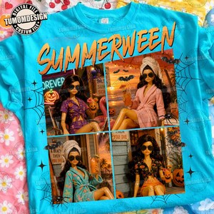May include: A bright blue t-shirt featuring the text SUMMERWEEN in orange letters. The graphic includes four panels showing dolls in various outfits, including a purple patterned set, a pink robe, a blue robe, and a black patterned top, with spiderweb accents.