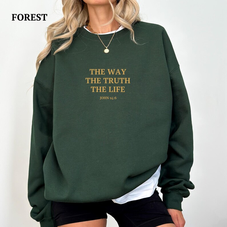 K&ouml;nnte beinhalten: Ein dunkelgr&uuml;ner Pullover mit dem Aufdruck "THE WAY THE TRUTH THE LIFE JOHN 14:6" in Gold.
