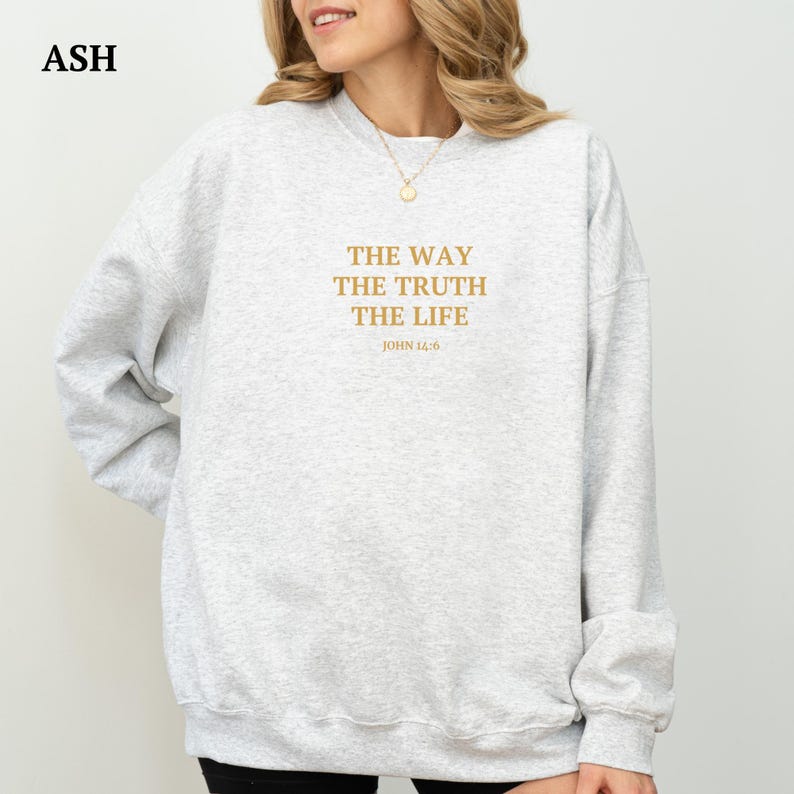 K&ouml;nnte beinhalten: Ein grauer Pullover mit dem Text "THE WAY THE TRUTH THE LIFE JOHN 14:6" in Gold auf der Vorderseite.