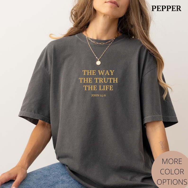 K&ouml;nnte beinhalten: Ein anthrazitfarbenes T-Shirt mit dem Text "THE WAY THE TRUTH THE LIFE" und "JOHN 14:6" in Gold auf der Vorderseite.
