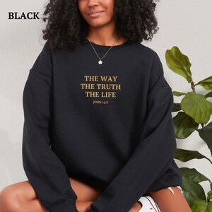 K&ouml;nnte beinhalten: Schwarzer Pullover mit dem Text "THE WAY THE TRUTH THE LIFE JOHN 14:6" in goldener Schrift.