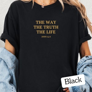 Op de afbeelding: Zwart T-shirt met de tekst "THE WAY THE TRUTH THE LIFE JOHN 14:6" in gouden letters.