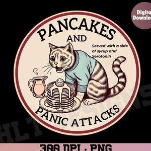 May include: A round, red-bordered sticker featuring a cartoon cat wearing a blue jumper and looking at a stack of pancakes. The text reads "Pancakes and Panic Attacks" with the tagline "Served with a side of syrup and serotonin".