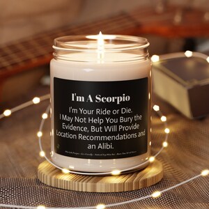 May include: A white candle with a black label that reads "I'm A Scorpio. I'm Your Ride or Die. May Not Help You Bury the Evidence, But Will Provide Location Recommendations and an Alibi."