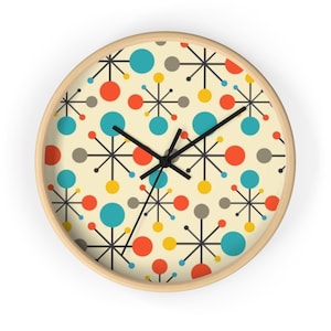 May include: A round wall clock with a light wood frame and a cream-colored face. The clock features a repeating pattern of black starburst lines connecting red, teal, yellow, and gray circles. It has three black hands for timekeeping.