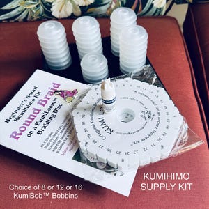 May include: A Kumihimo supply kit with a white braiding disc, white bobbins, and a small bottle of glue. The kit includes a beginner's guide and offers a choice of 8, 12, or 16 KumiBob bobbins. The text on the disc reads "Kumihimo Octagonal".