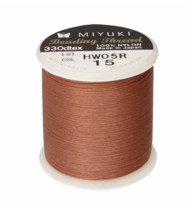 May include: A spool of MIYUKI Beading Thread in a warm brown color. The label indicates it is 100% nylon, 330dtex, and made in Japan. The spool is labeled with the code HWO5R and color 15.