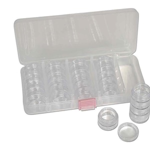 May include: A clear plastic storage box with a pink latch, containing 24 small clear plastic containers. The containers are stacked in rows and are perfect for organizing small items.