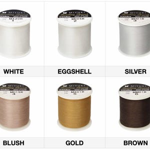 May include: Spools of MIYUKI beading thread in various colors: white, eggshell, silver, blush, gold, and brown. Each spool is labeled with the color name and product information. The thread is 330dtex nylon.