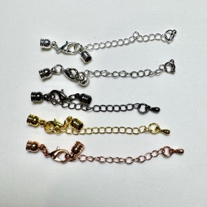 May include: A white ceramic mug with a black handle and the text "But First, Coffee" in a bold, black font. The mug is set against a blurred background, suggesting a cozy setting.