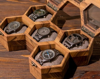May include: A wooden hexagonal box with six compartments, each containing a different wooden wristwatch. The box is made of dark wood with a natural grain pattern. The watches have black faces and brown bands.