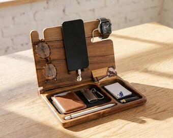 May include: A wooden desk organizer with a phone, glasses, and watch. The organizer has a tray for small items like a wallet, lighter, and pen. The wood has a natural grain and is set on a wooden table.