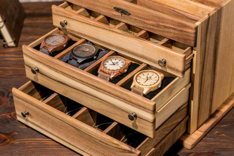 May include: Wooden watch box with multiple drawers. The drawers are open and reveal several wooden watches with different colored bands.