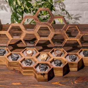 K&ouml;nnte beinhalten: Eine Holzuhrbox mit einem Wabenmuster. Die Box hat 12 F&auml;cher zum Aufbewahren von Uhren. Die Box ist aus dunklem Holz und hat eine nat&uuml;rliche Oberfl&auml;che.