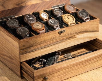 May include: A rectangular wooden watch box with a hinged lid and a pull-out drawer. The top compartment features eight slots with black cushions, each holding a wooden wristwatch. The bottom drawer contains various small metal accessories and coins.