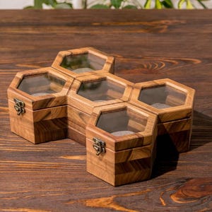 K&ouml;nnte beinhalten: Eine sechseckige Holzkiste mit sechs F&auml;chern, jedes mit einem Glasdeckel. Die Kiste ist aus hellbraunem Holz mit einer nat&uuml;rlichen Oberfl&auml;che.
