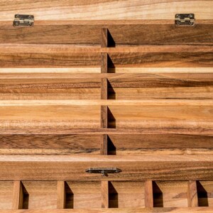 May include: A wooden box with multiple compartments, perfect for organizing small items. The box has a hinged lid and a latch to keep it closed.