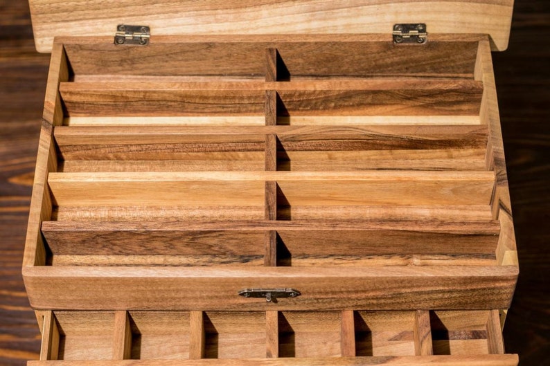 May include: A wooden box with multiple compartments, perfect for organizing small items. The box has a hinged lid and a latch to keep it closed.