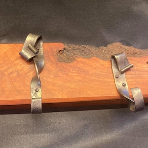 Puede incluir: Tres ganchos de metal rústico montados en una tabla de madera con un acabado de veta de madera natural.