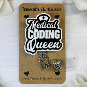 May include: A black and white badge reel with the text "Medical Coding Queen" and a small nurse's cap with a cross on top. The badge reel is attached to a clear plastic badge holder.
