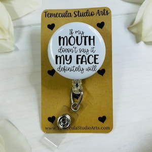 May include: White round badge holder with a black retractable cord and a white button. The badge features the text "If my mouth doesn't say it my face definitely will".