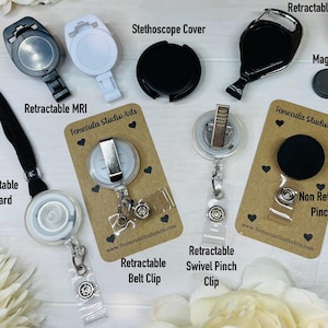 May include: A collection of badge accessories including a black retractable lanyard, a white retractable MRI badge reel, a black stethoscope cover, a black retractable carabiner, a small magnet, and badge reels with belt clips and pinch clips.