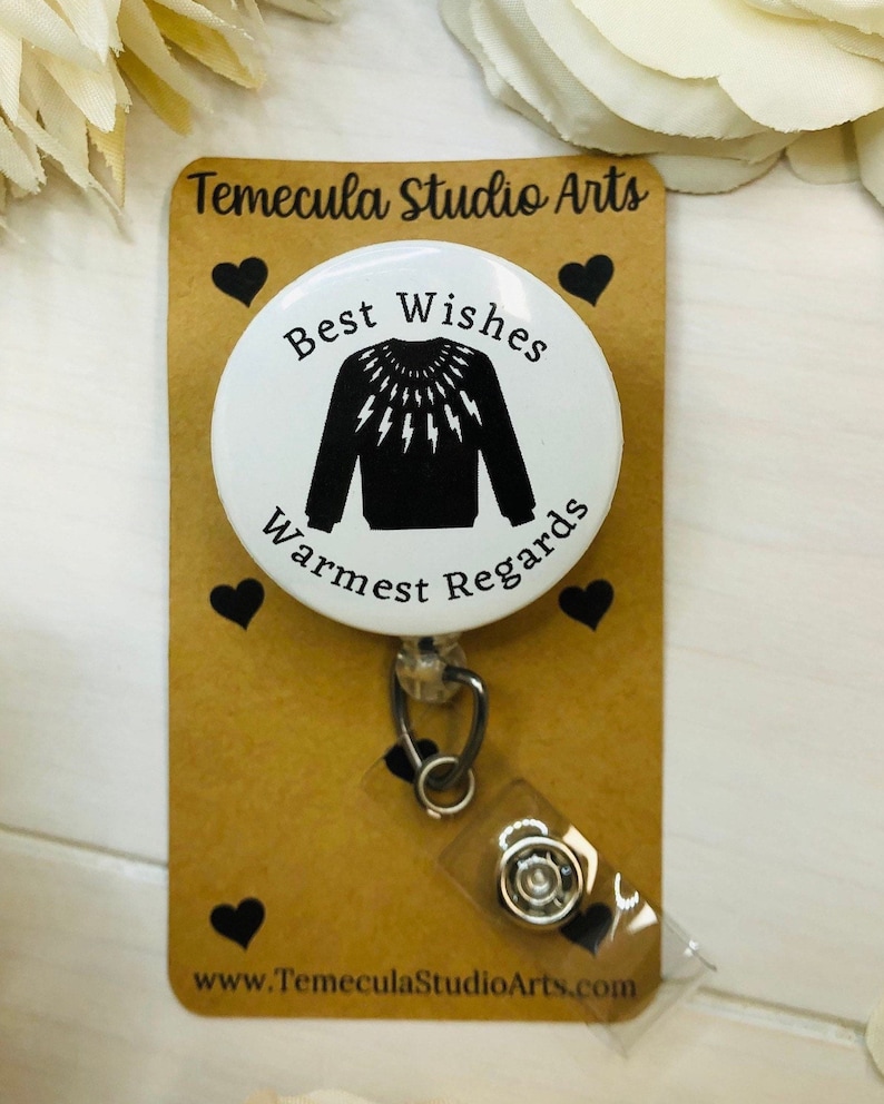 Puede incluir: Un portatarjetas blanco con el texto "Best Wishes Warmest Regards" y un dise&ntilde;o de su&eacute;ter negro. La tarjeta est&aacute; unida a una tarjeta marr&oacute;n con forma de coraz&oacute;n negro y el texto "Temecula Studio Arts".