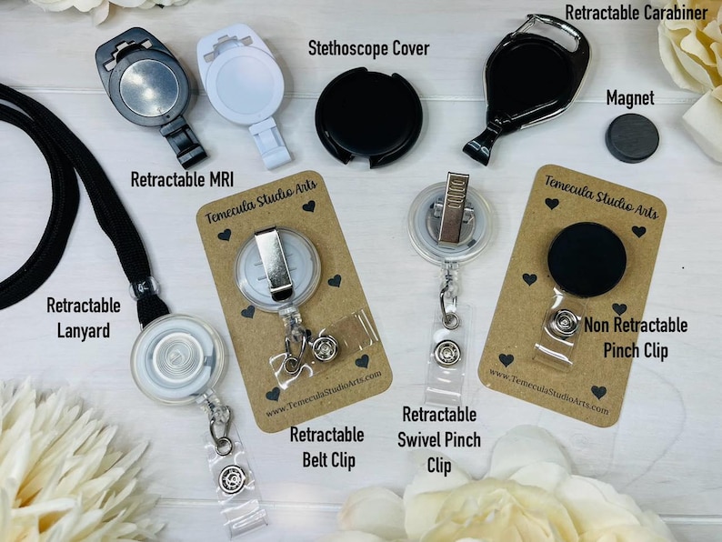 May include: Assortment of retractable badge reels and clips, including a lanyard, a stethoscope cover, a swivel pinch clip, a belt clip, a carabiner, and a magnet. The reels are clear plastic with silver metal accents. The clips are black plastic. The lanyard is black.