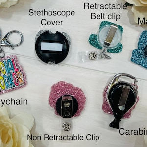 May include: A collection of accessories including a keychain with the text SOCIAL WORKER, a black stethoscope cover, a teal glitter retractable belt clip, a teal glitter magnet, a pink glitter non-retractable clip, and a pink glitter carabiner.