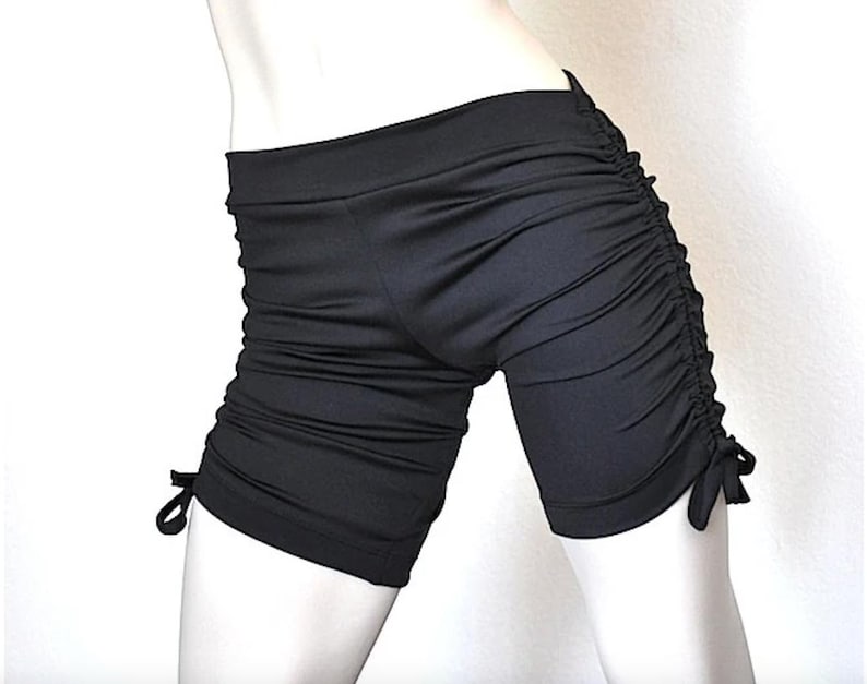 May include: Black athletic shorts with a drawstring detail on the sides. The shorts are made of a stretchy, comfortable fabric.