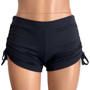 May include: Black swim shorts with adjustable drawstring ties on the sides.