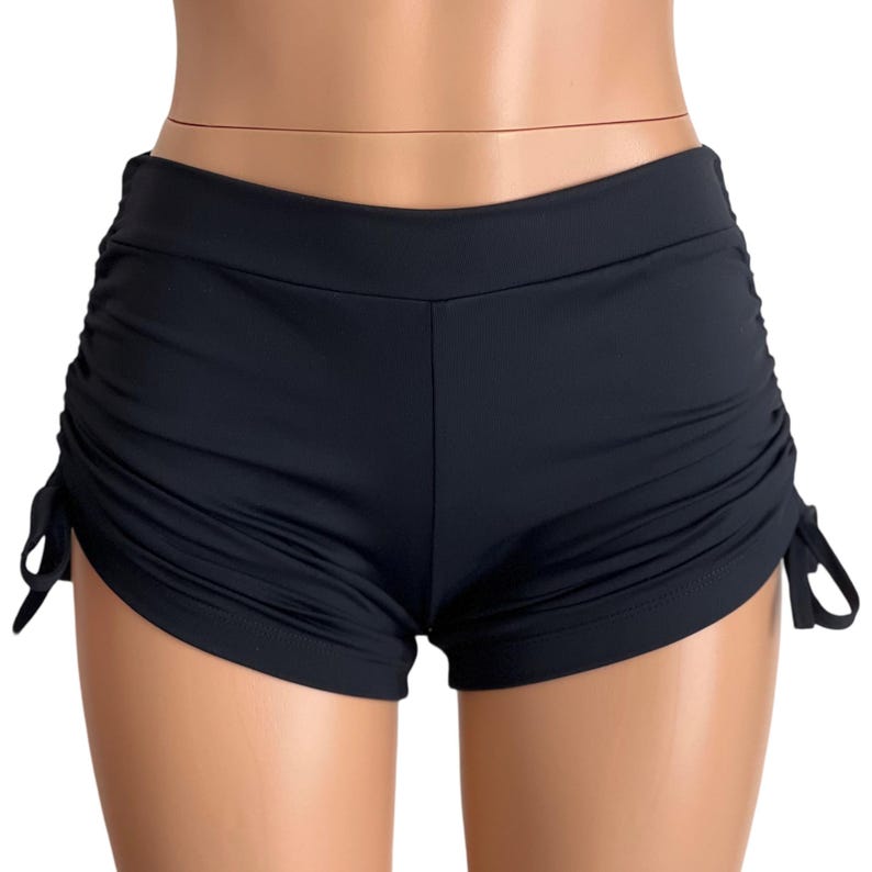May include: Black swim shorts with adjustable drawstring ties on the sides.