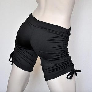 May include: Black athletic shorts with a gathered detail on the sides and tie closures at the bottom.