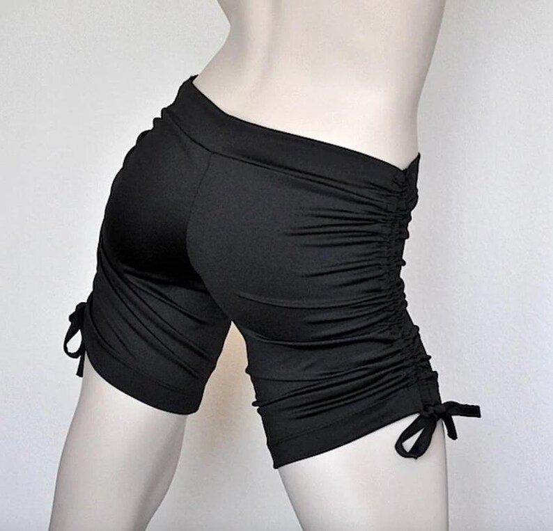 May include: Black athletic shorts with a gathered detail on the sides and tie closures at the bottom.