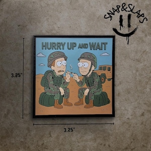 Könnte beinhalten: Quadratische Illustration mit zwei Zeichentrickfiguren in Militäruniform, mit dem Text "HURRY UP AND WAIT". Das Kunstwerk ist 8,26 cm groß und zeigt eine Wüstenlandschaft mit einem Fahrzeug im Hintergrund. Es hat einen schwarzen Rahmen und das Snap & Slaps Logo.