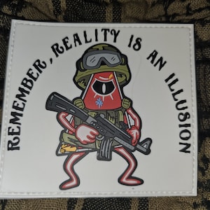 May include: White patch with a red and green cartoon character holding a black rifle. The text around the character reads "Remember, reality is an illusion."