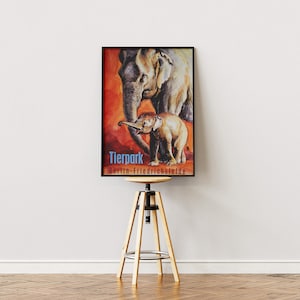 May include: A vintage poster advertising the Tierpark Berlin-Friedrichsfelde zoo. The poster features a watercolour illustration of an adult elephant and a baby elephant on a red background. The text on the poster reads "Tierpark Berlin-Friedrichsfelde".