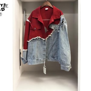 May include: A red and blue denim jacket with a unique design. The jacket features a red upper section and a light blue denim lower section. The jacket is hanging on a wooden hanger inside a white closet. The text "ALL STYLE SQUAD" is visible.