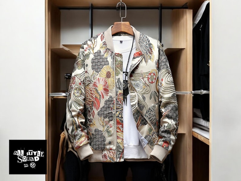 May include: A beige bomber jacket with a floral print. The jacket has a zipper closure and a ribbed collar, cuffs, and hem.