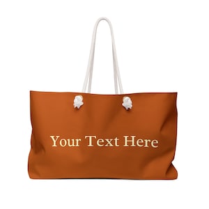 Puede incluir: Una bolsa de lona grande de color naranja con asas de cuerda blanca y el texto "Your Text Here" en color amarillo claro.