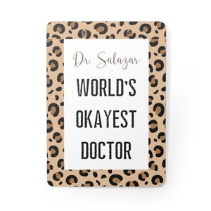 May include: A brown and black leopard print clipboard with the text "Dr. Salazar World's Okayest Doctor" on a white background.