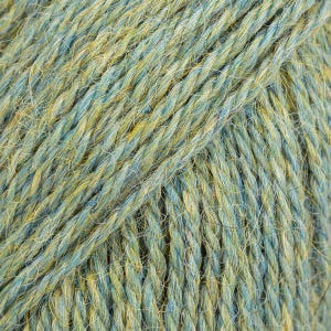 Puede incluir: Un hilo de varias hebras que presenta una mezcla de fibras de color azul suave y amarillo dorado retorcidas entre s&iacute;. La textura parece ligeramente difusa con una estructura de torsi&oacute;n visible, creando un efecto de color variado.